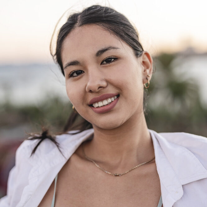 Close up portrait of a smiling asian young female near the sea